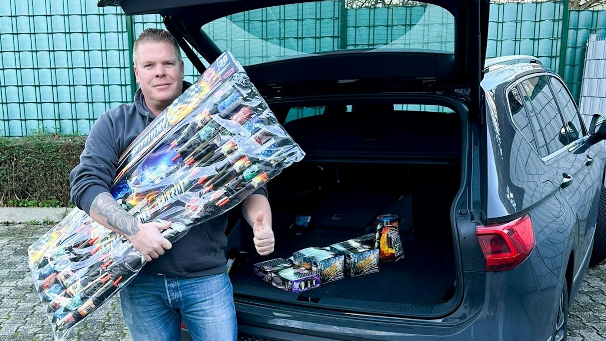 Der Bad Münstereifeler Markus Ramacher steht vor seinem Auto und hält zahlreiche Silvesterraketen in der Hand.