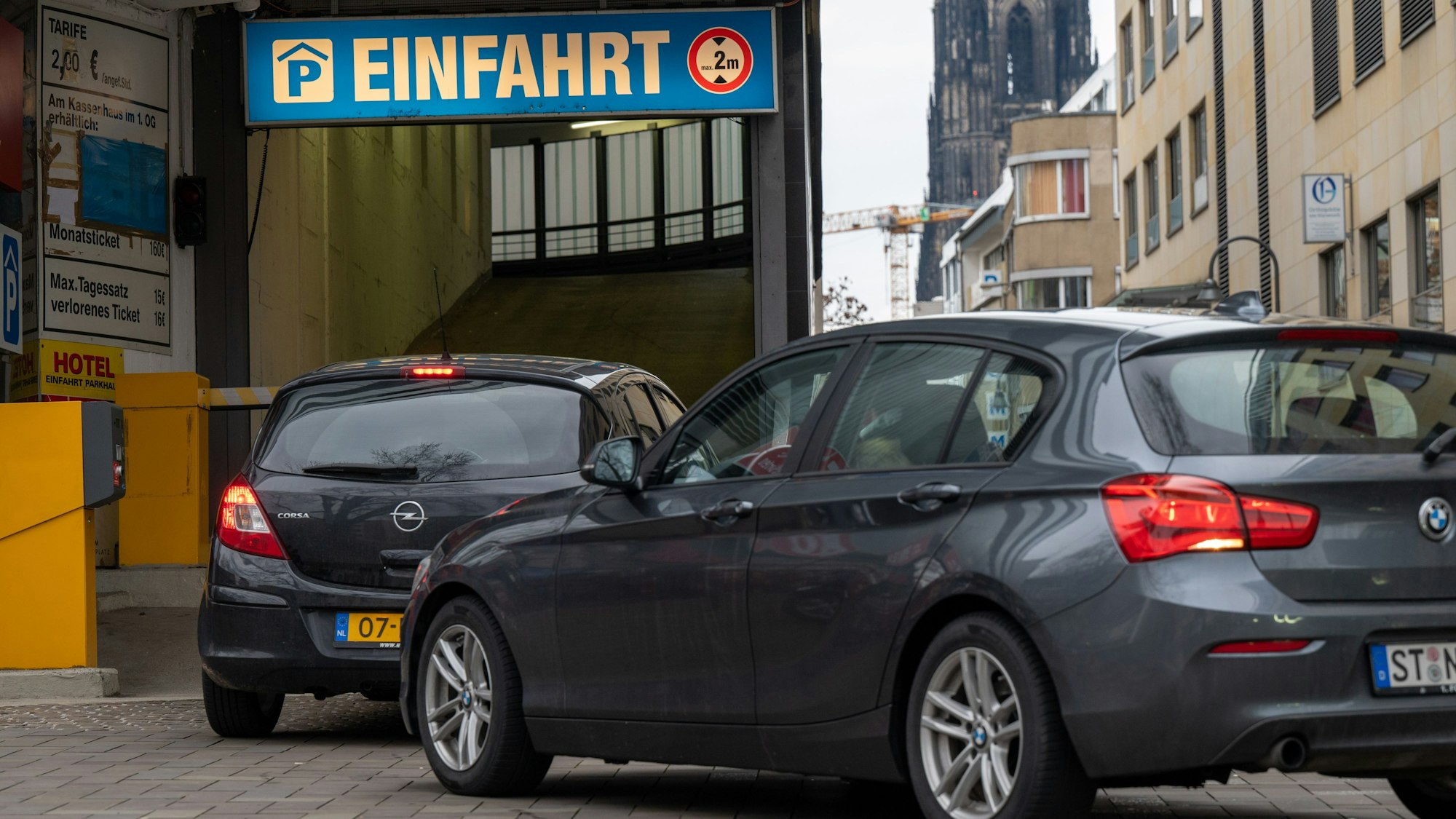 Zwei Autos stehen vor der Einfahrt in ein Parkhaus.