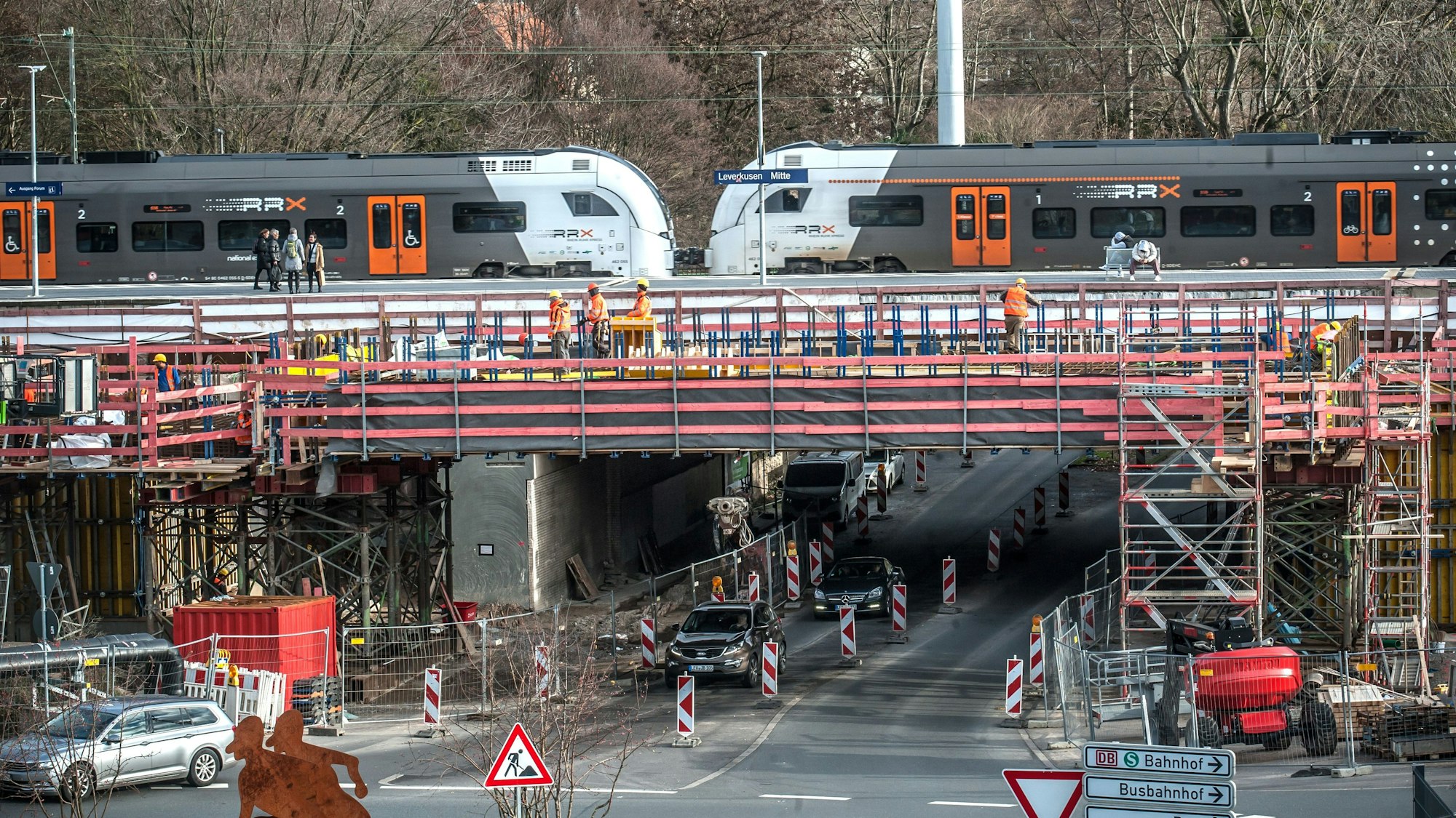 Blick auf die im Bau befindliche Brücke an der Rathenaustraße am Bahnhof Leverkusen-Mitte. Es sind Bauarbeiter zu sehen. Am Bahnhof steht ein Zug des Rhein-Ruhr-Express.
