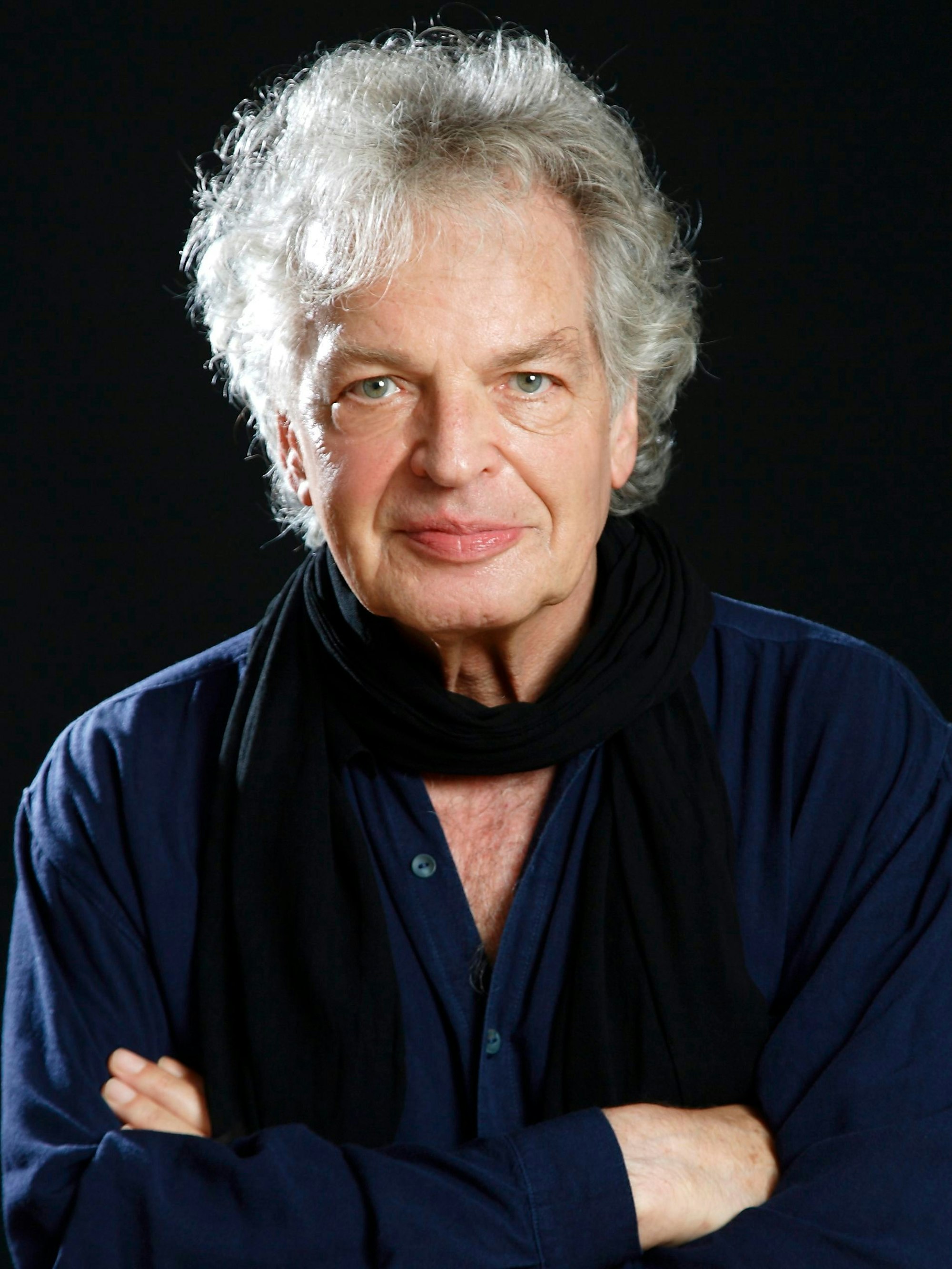 Joachim Kühn blickt mit verschränkten Armen in die Kamera.