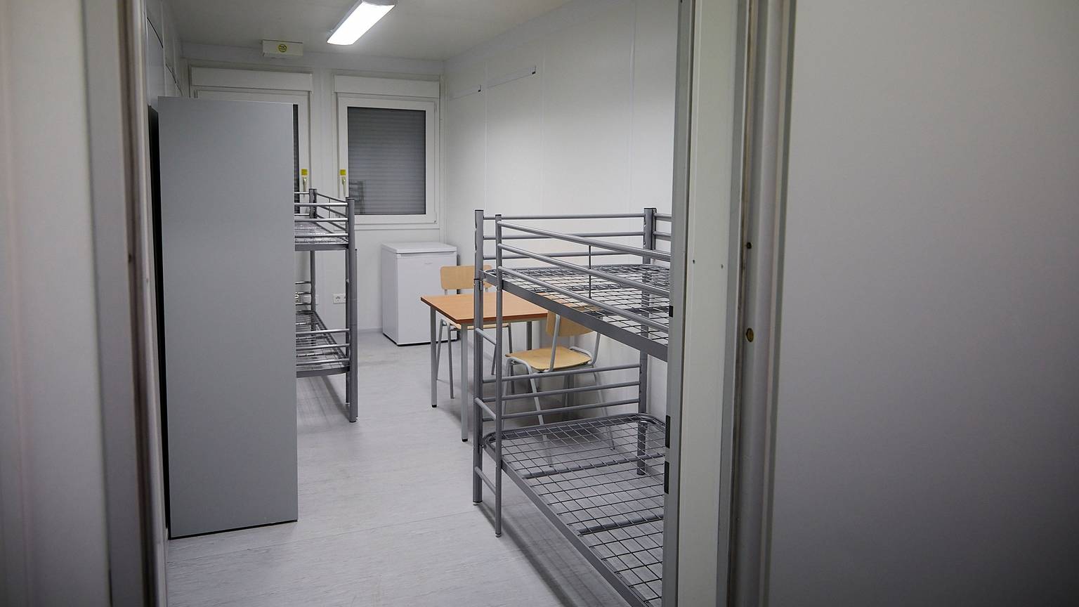Ein Schlafraum mit zwei Etagenbetten, einem kleinen Tisch und zwei Stühlen.
