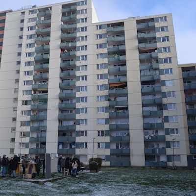 Die Hochhäuser der Theodor-Heus-Straße 2-4 mit einigen Bewohnern und Bewohnerinnen im Vordergrund