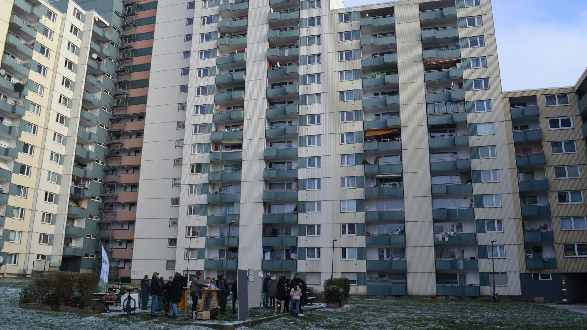 Die Hochhäuser der Theodor-Heus-Straße 2-4 mit einigen Bewohnern und Bewohnerinnen im Vordergrund