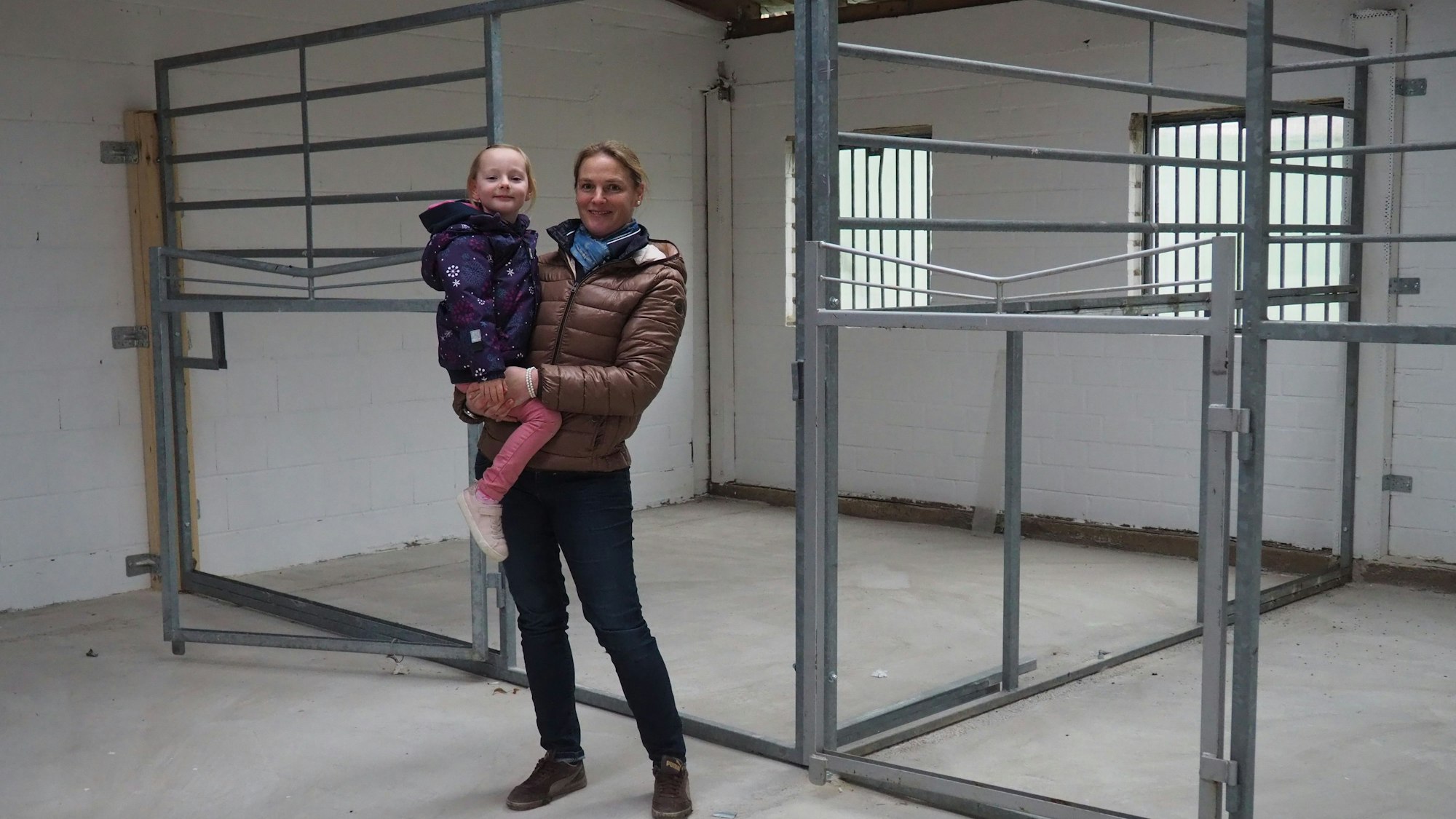 Das Bild zeigt Anne Spoo mit Tochter Paulina vor den Pferdeboxen.