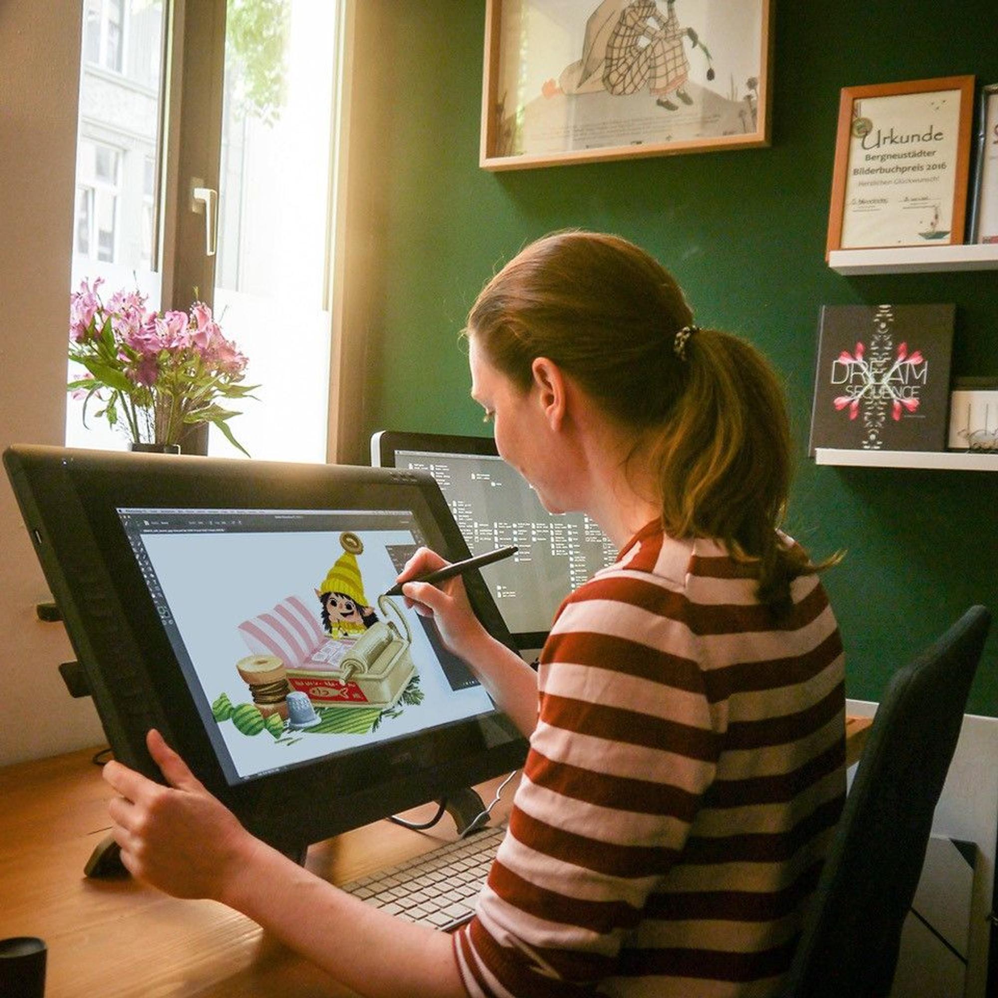 Sabine Dully sitzt am Schreibtisch und malt eine „Jeppe & Oswald“-Illustration auf ihrem Computer.
