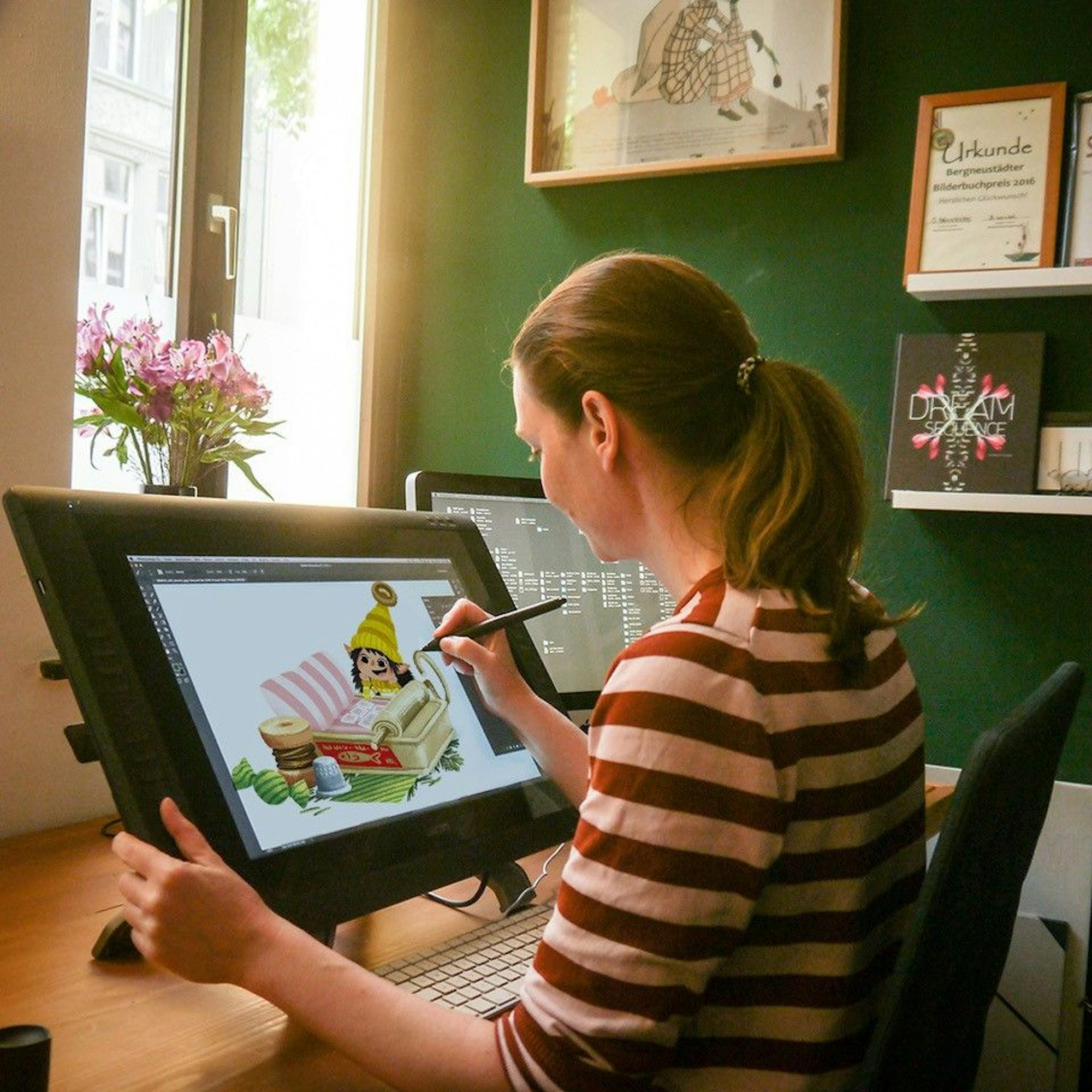 Sabine Dully sitzt am Schreibtisch und malt eine „Jeppe & Oswald“-Illustration auf ihrem Computer.