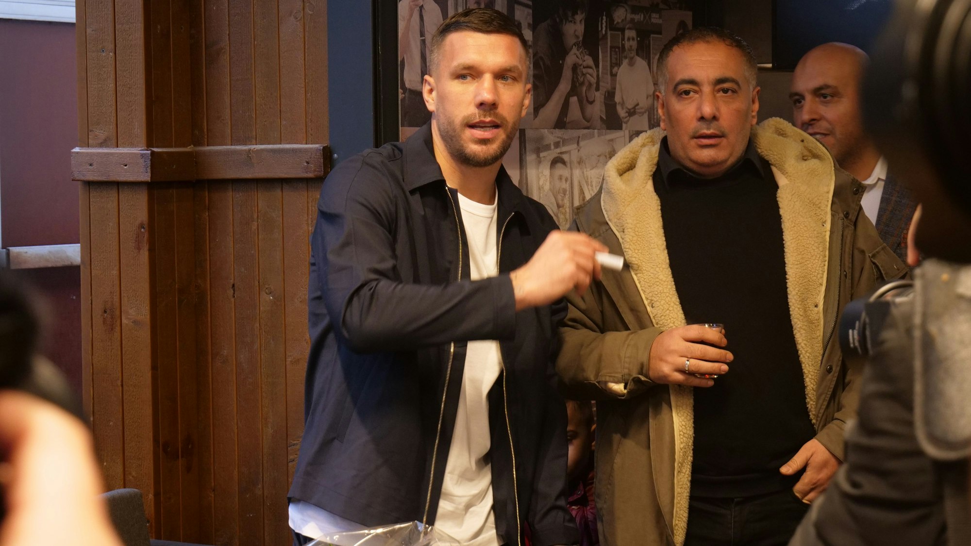 Das Foto zeigt Lukas Podolski bei der Eröffnung seines Mangal Dönerladens in Hürth. Der Fußballer gibt fleißig Autogramme.
