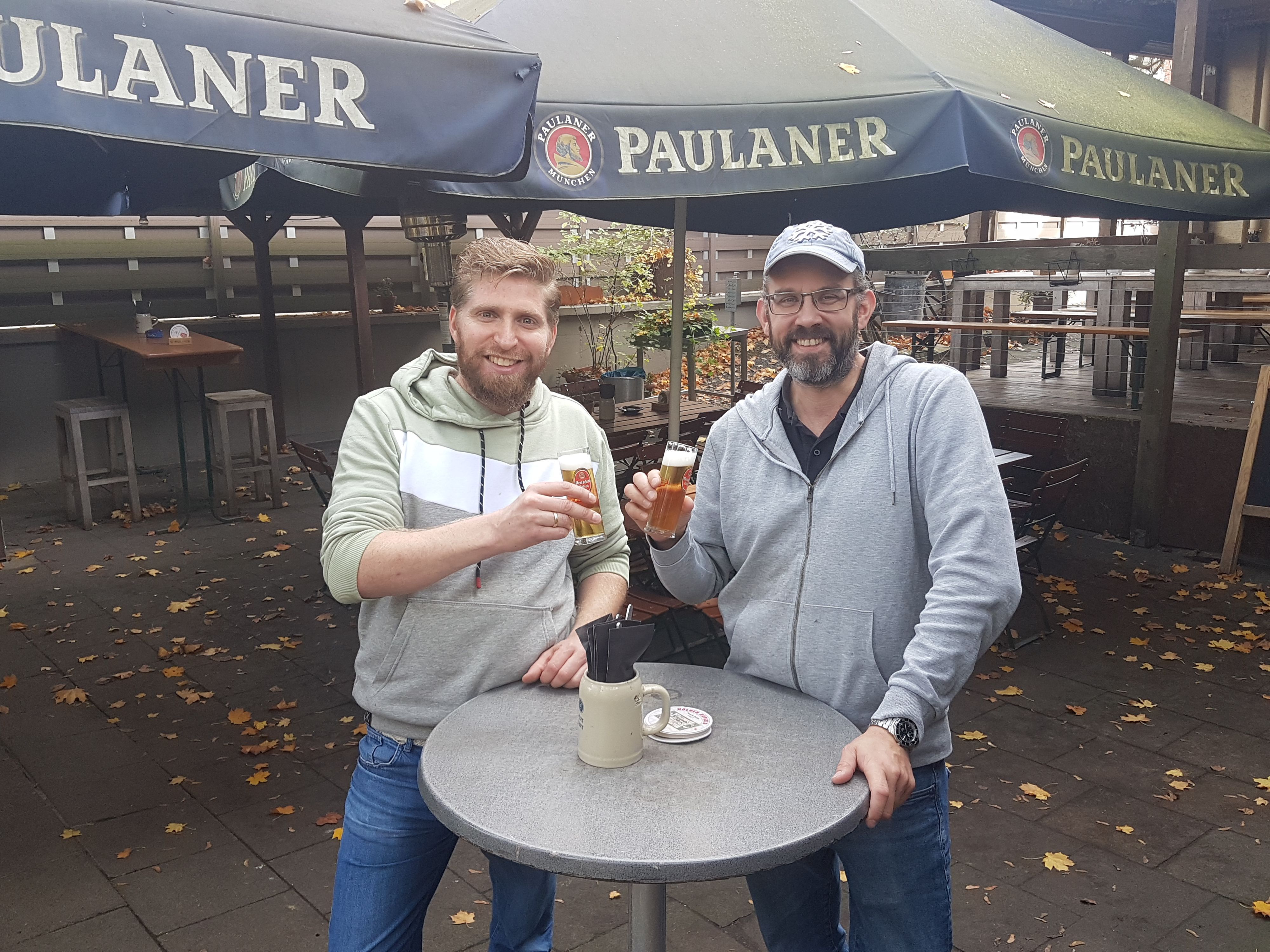 Die beiden Betreiber des KLausmann stehen im Hof und stoßen mit Kölsch an.