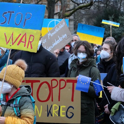 Menschen mit Plakaten auf den "Stop War" und "Stoppt den Krieg" zu lesen ist, stehen bei einer Demonstration gegen den Krieg in der Ukraine auf dem Konrad-Adenauer-Platz in Bergisch Gladbach.