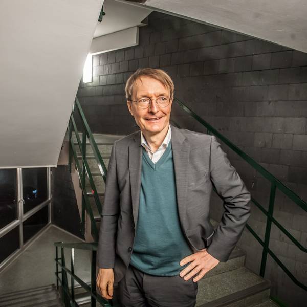 Karl Lauterbach steht in einem Treppenhaus, er schaut an der Kamera vorbei.