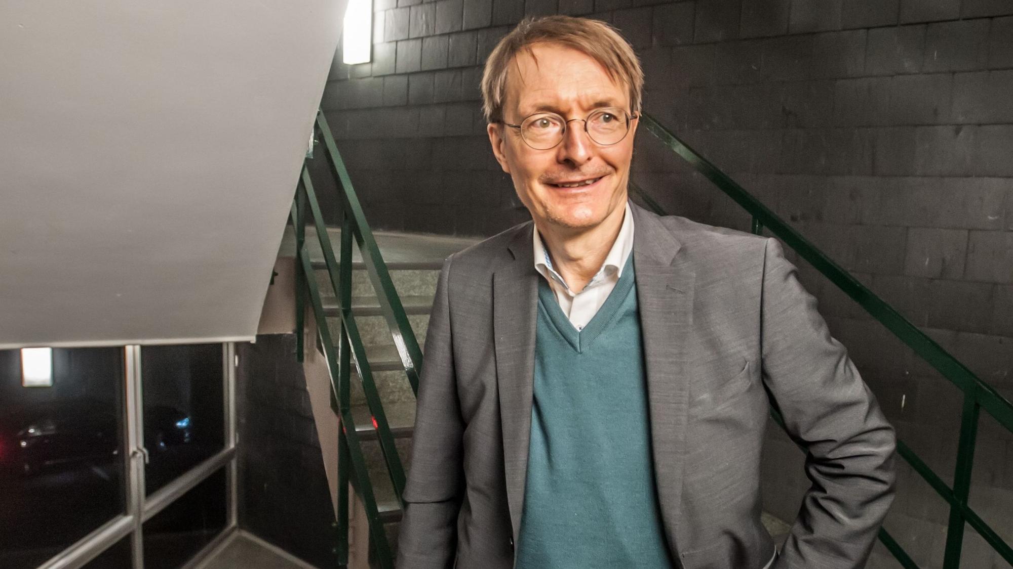 Karl Lauterbach steht in einem Treppenhaus, er schaut an der Kamera vorbei.