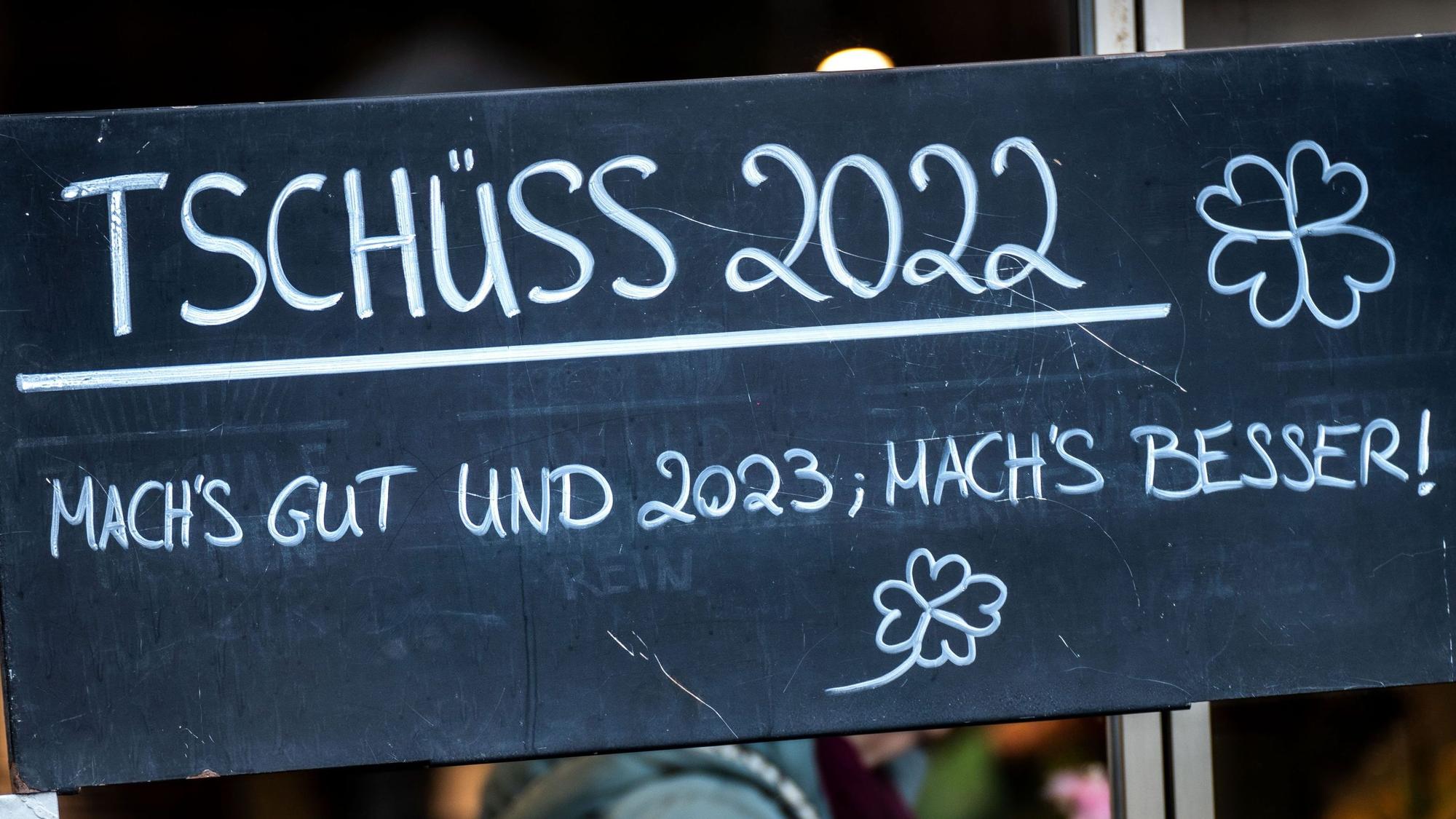 „Tschüss 2022 - Mach's gut und 2023: Mach's besser!“ steht auf einem Schild an einem Blumengeschäft in der Bad Homburger Innenstadt, in dem Töpfchen mit Kleeblättern und hineingesteckten Figuren von Schweinchen und Schornsteinfegern als Glücksbringer angeboten werden.