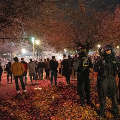 Polizisten stehen in der Nähe von Feiernden.