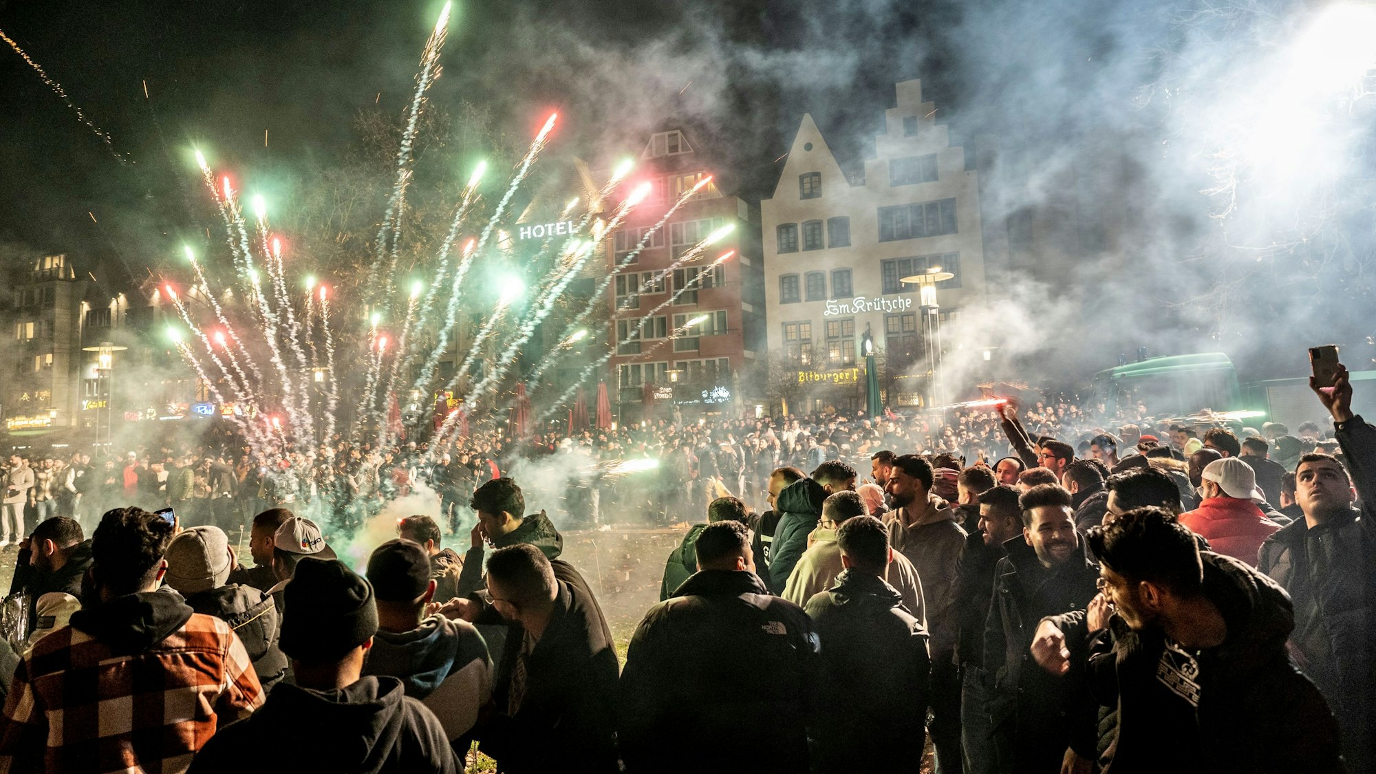 Böller und Feuerwerk explodieren in der Kölner Altstadt. Eine Menschenmenge, fast ausschließlich Männer, schaut zu.