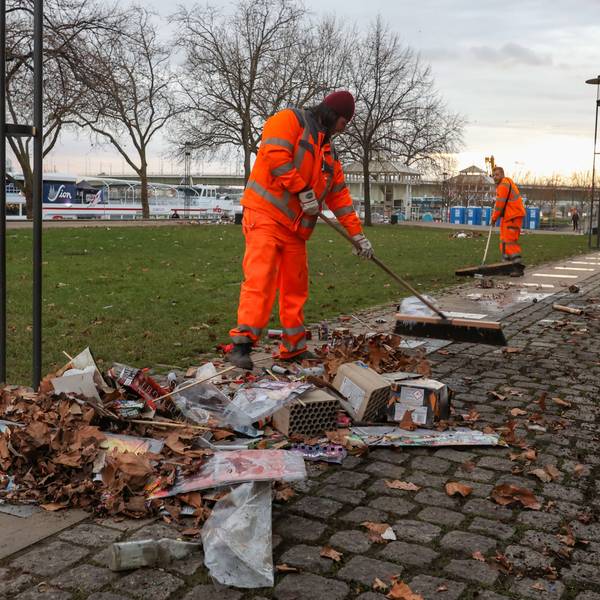 Zwei Mitarbeiter der AWB kehren den Silvestermüll am Rheingarten in der Altstadt zusammen.