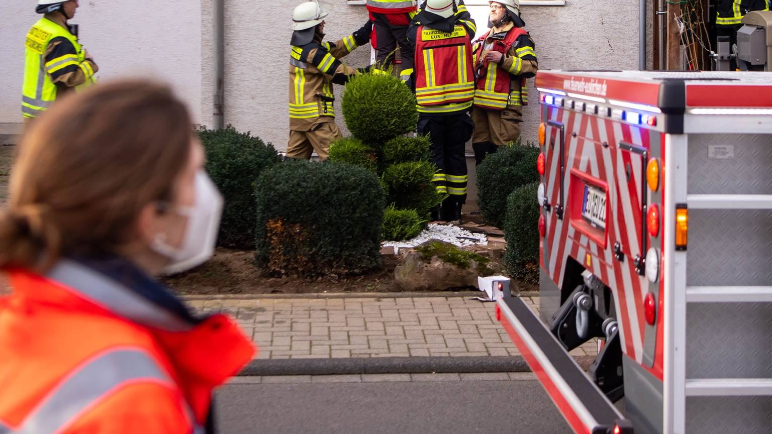 Feuerwehrleute stehen an einem Haus, in dem es gebrannt hat.