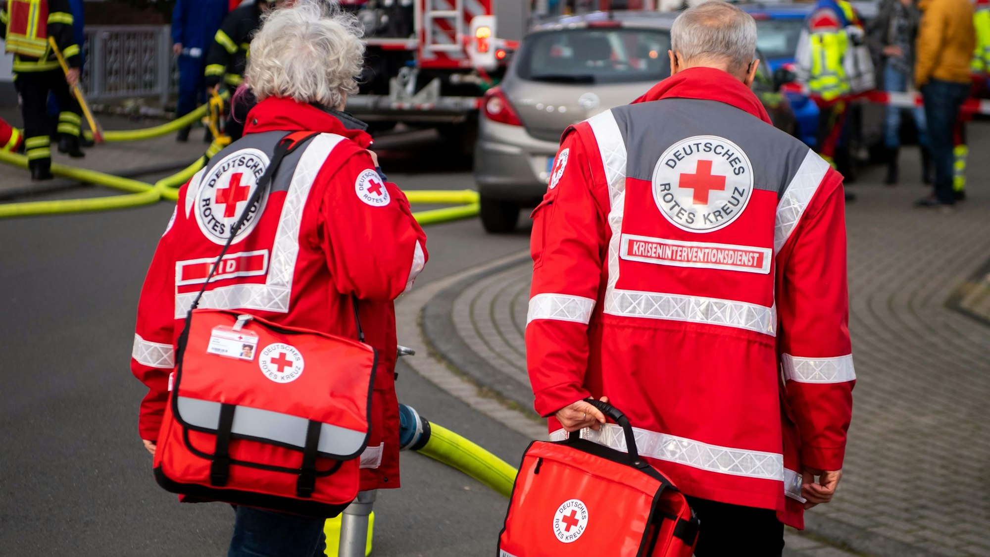Zwei Mitarbeiter des Kriseninterventionsdienstes sind von hinten zu sehen, wie sie zur Einsatzstelle gehen.