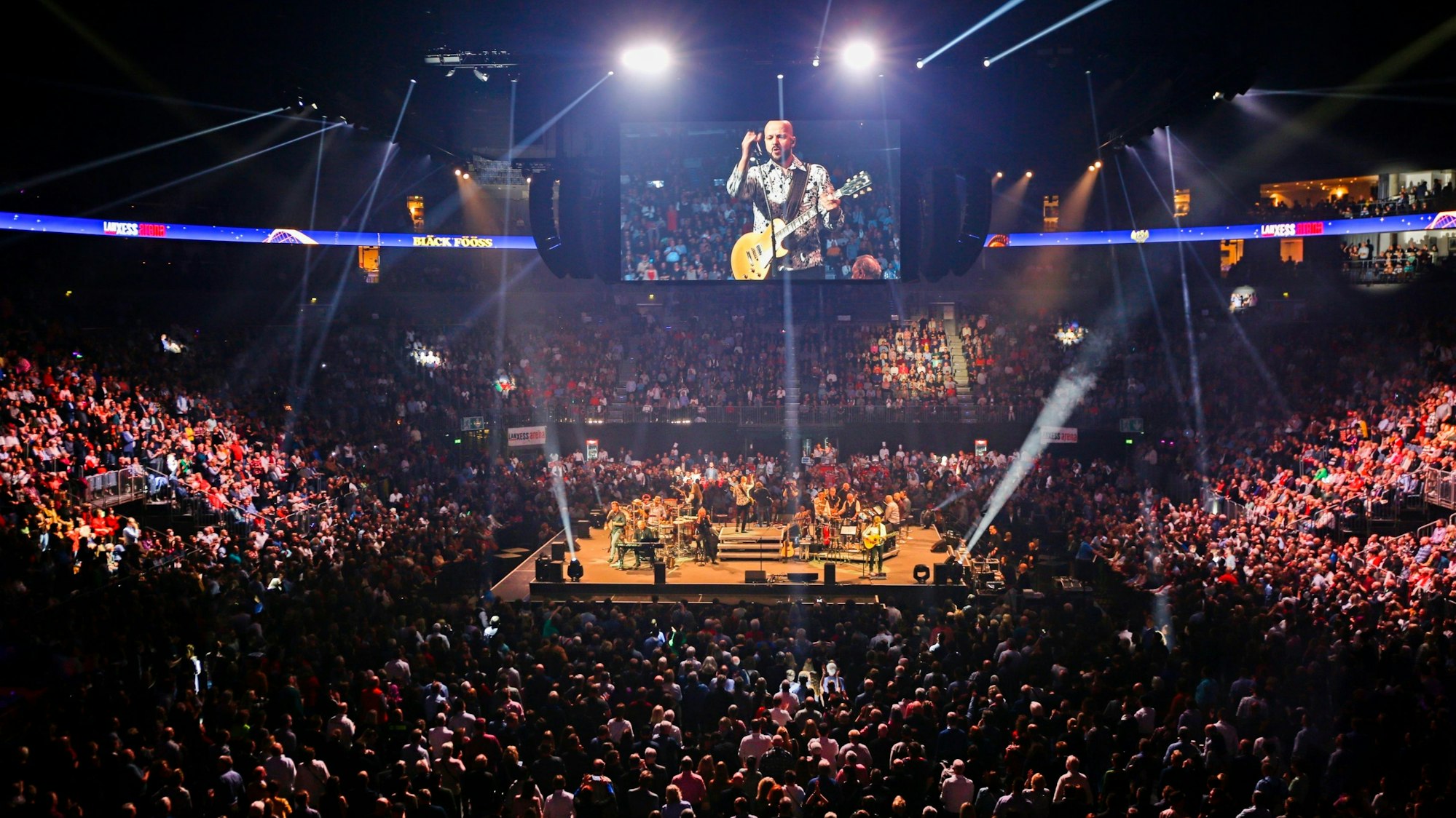 Das Bild zeigt die volle Lanxess Arena und die Bühne beim Silvesterkonzert der Bläck Fööss.