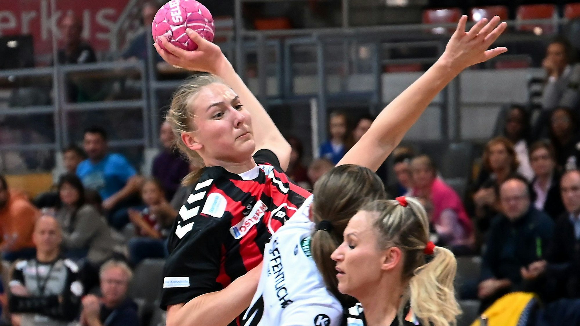 Eine Handballspielerin setzt sich gegen ihre Gegnerin durch und wirft.