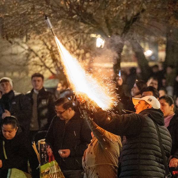 Das Bild zeigt einen Mann, der eine Feuerwerkrakete starten lässt.