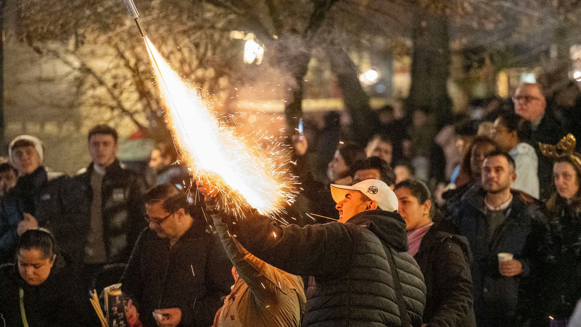 Das Bild zeigt einen Mann, der eine Feuerwerkrakete starten lässt.