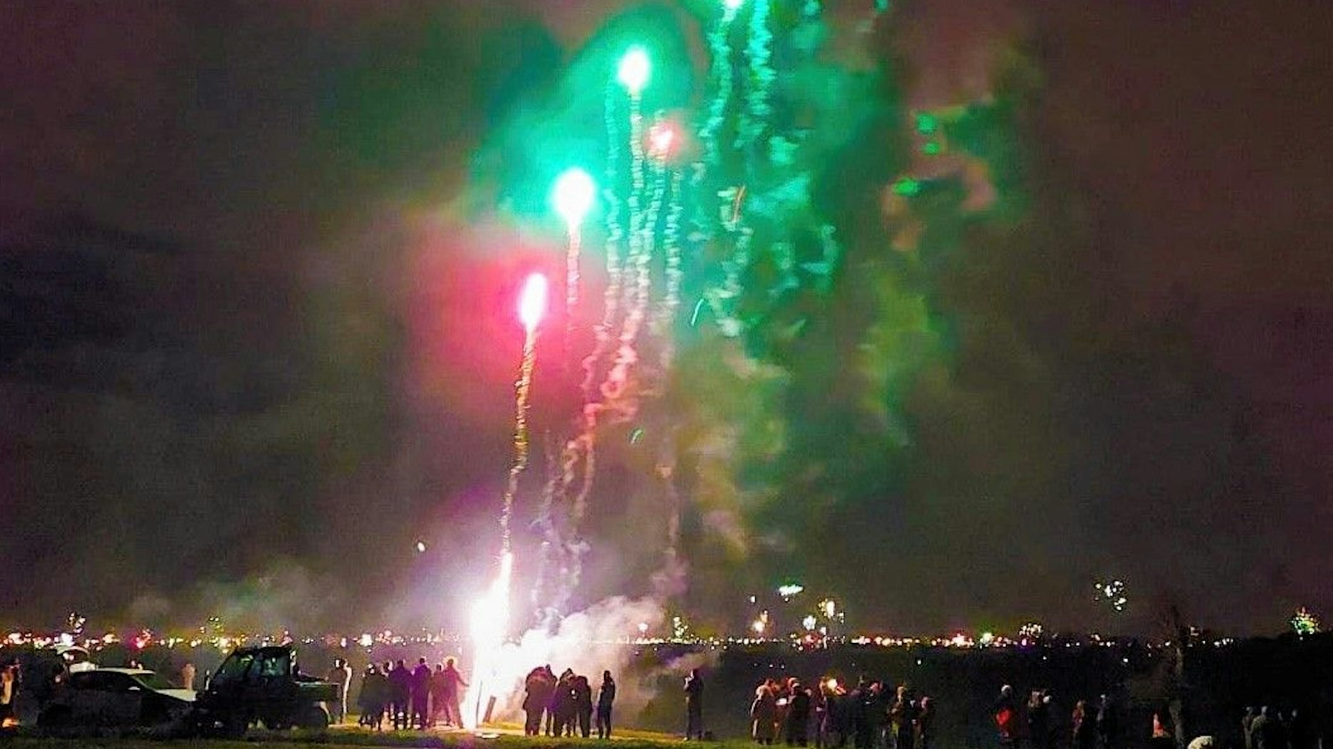 Menschen stehen in Imbach, um das Silvesterfeuerwerk in Leverkusen zu bewundern