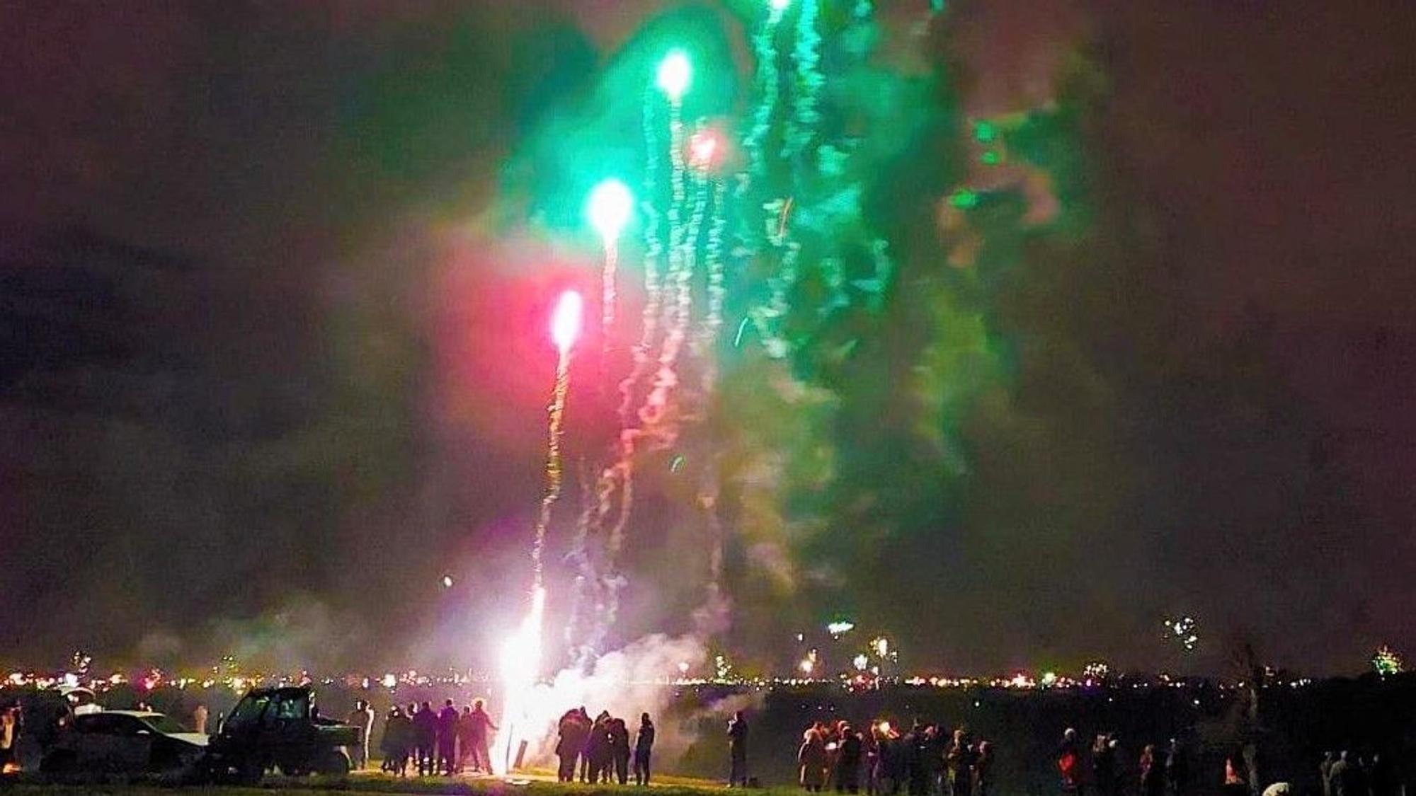 Menschen stehen in Imbach, um das Silvesterfeuerwerk in Leverkusen zu bewundern