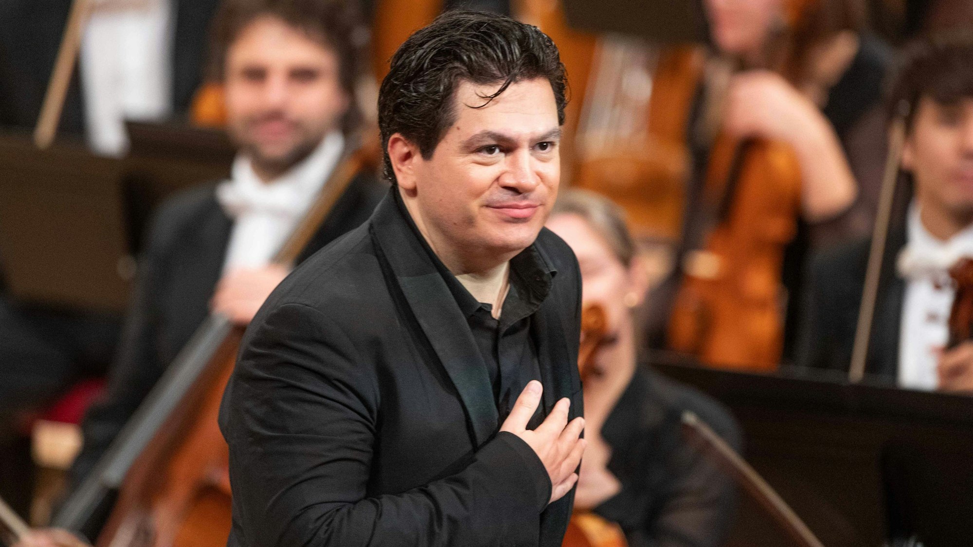 Cristian Măcelaru steht, die Hand aufs Herz gelegt, vor den Musikern des WDR Sinfonieorchesters.