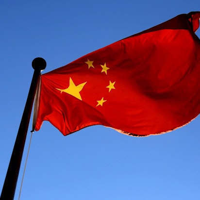 Man sieht die Flagge Chinas vor dem blauen Himmel.