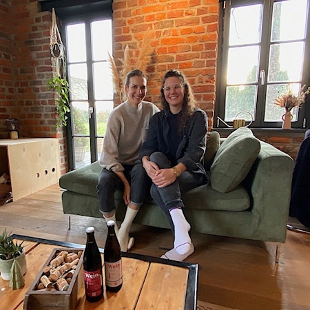 Leonie Berents und Silja Mende-Kamps (rechts) sitzen auf einer Couch.