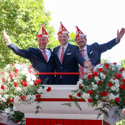 Bei der Vorstellung des designierten Kölner Dreigestirns 2023
sind André Fahnenbruck , Boris Müller und Marco Schneefeld zu sehen. Sie stehen einigen Blumen und halten die Arme in die Luft.