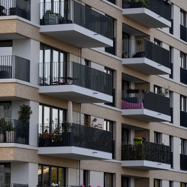 Zu sehen sind mehrere neu gebaute Wohnhäuser, deren Balkone dicht aneinander  liegen.
