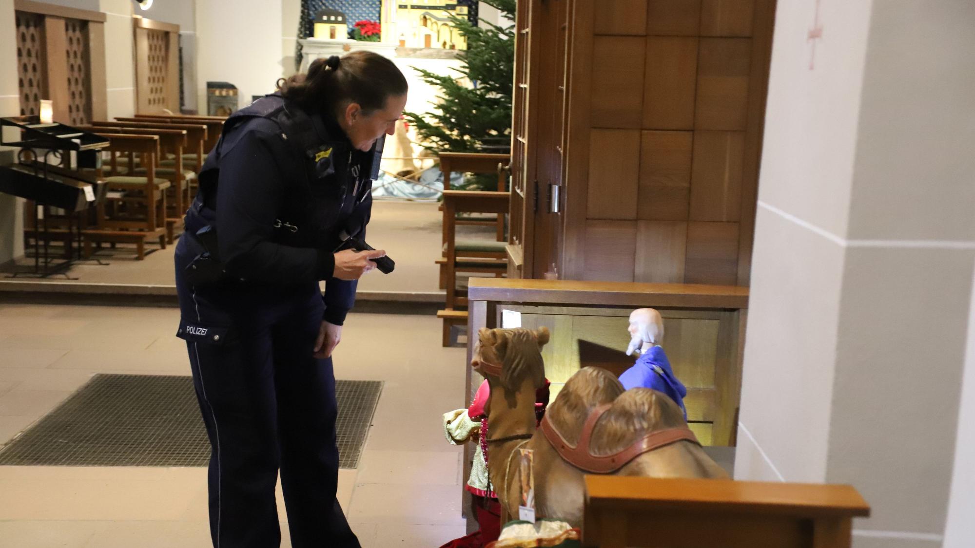 Eine Polizistin begutachtet die Krippenfiguren in der Siegburger Abteikirche.