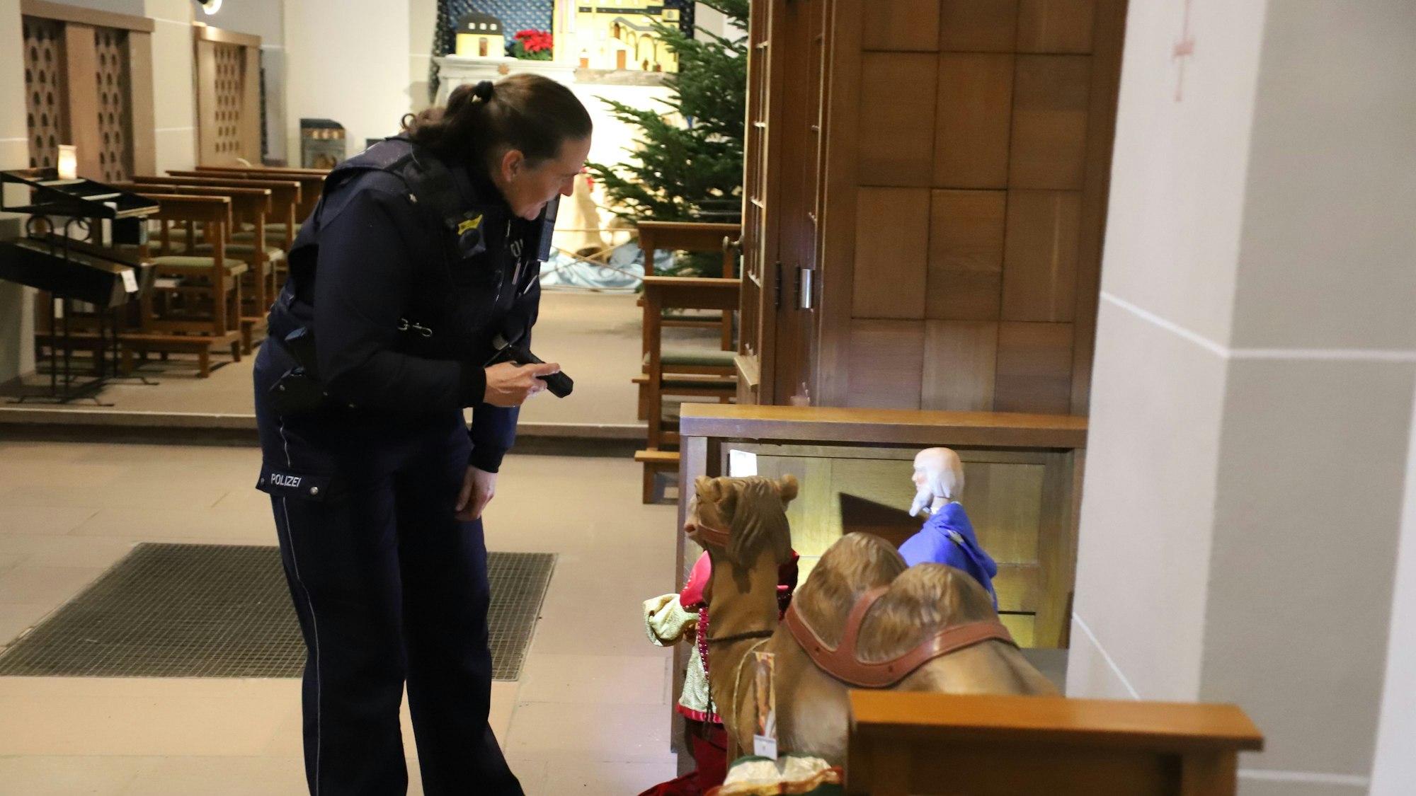 Eine Polizistin begutachtet die Krippenfiguren in der Siegburger Abteikirche.