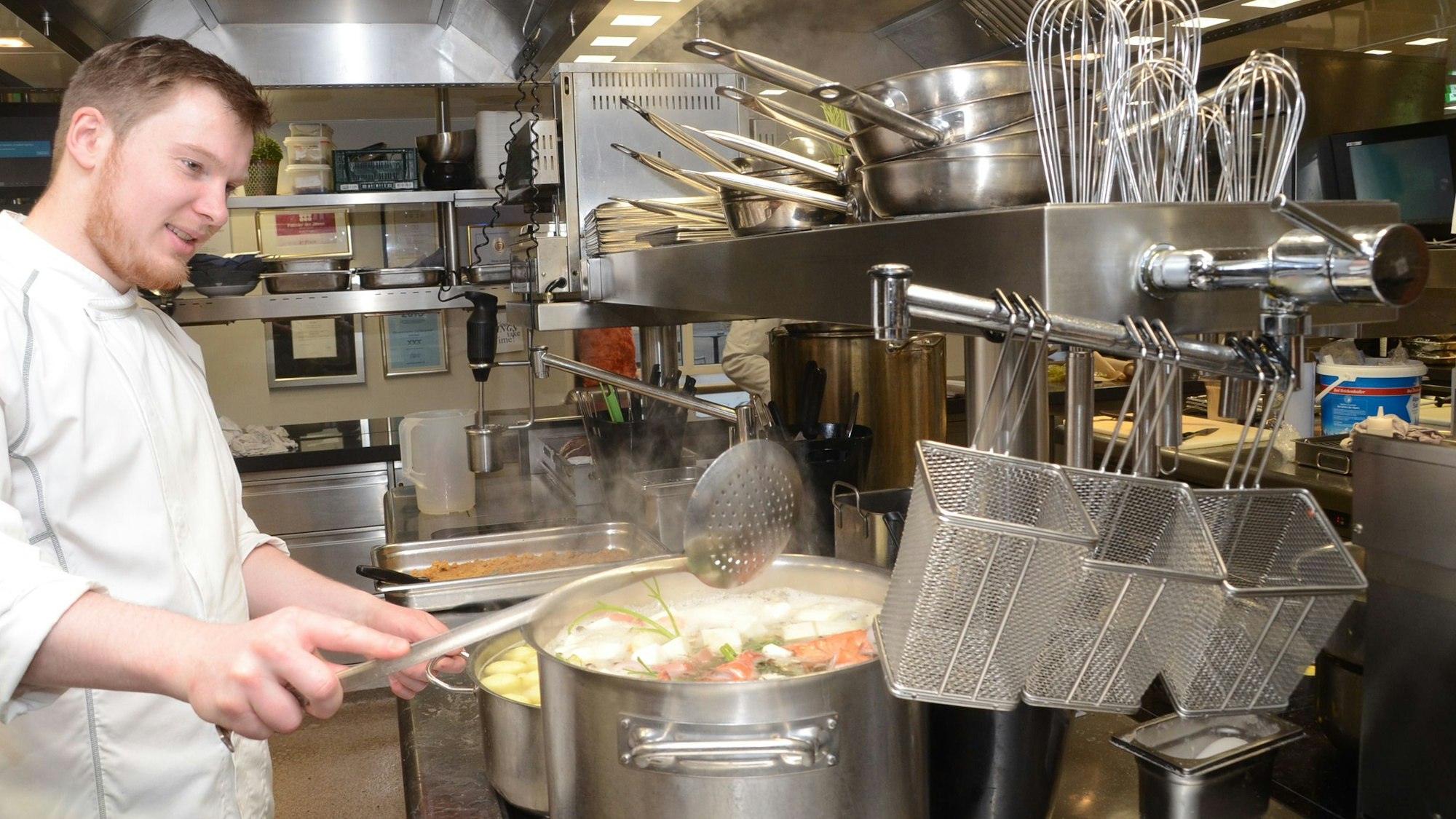 Koch in Großküche am Suppentopf.