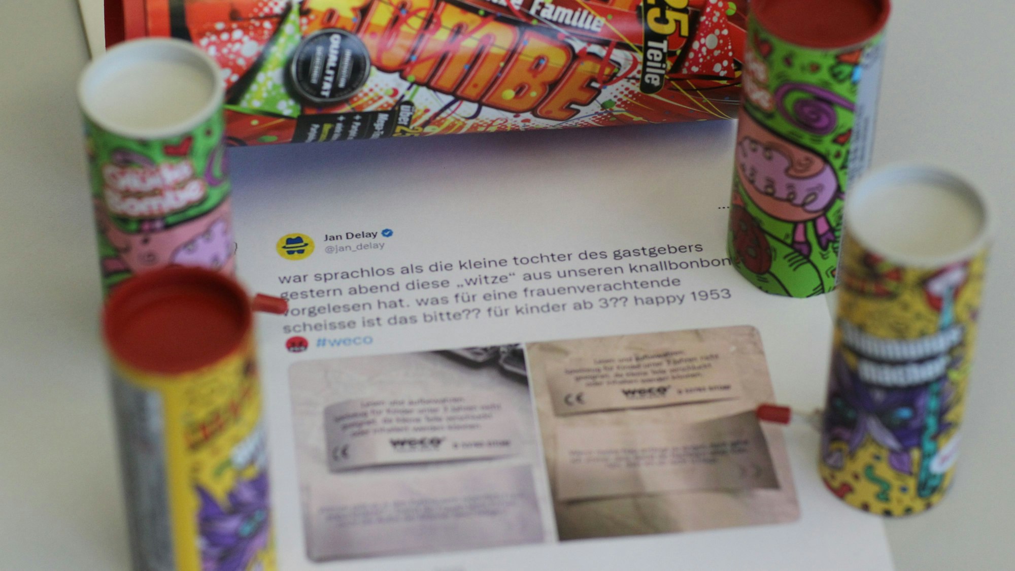 Der ausgedruckte Tweet von Jan Delay liegt auf einem Tisch, darum Knallbonbon-Verpackungen.