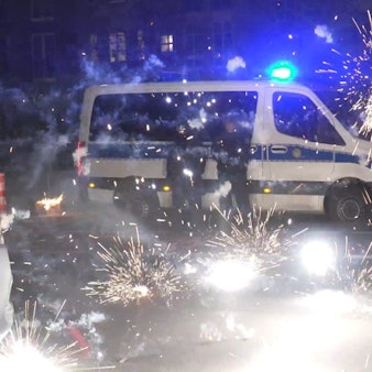 Polizeibeamte stehen hinter explodierendem Feuerwerk in der Silvesternacht in Berlin.