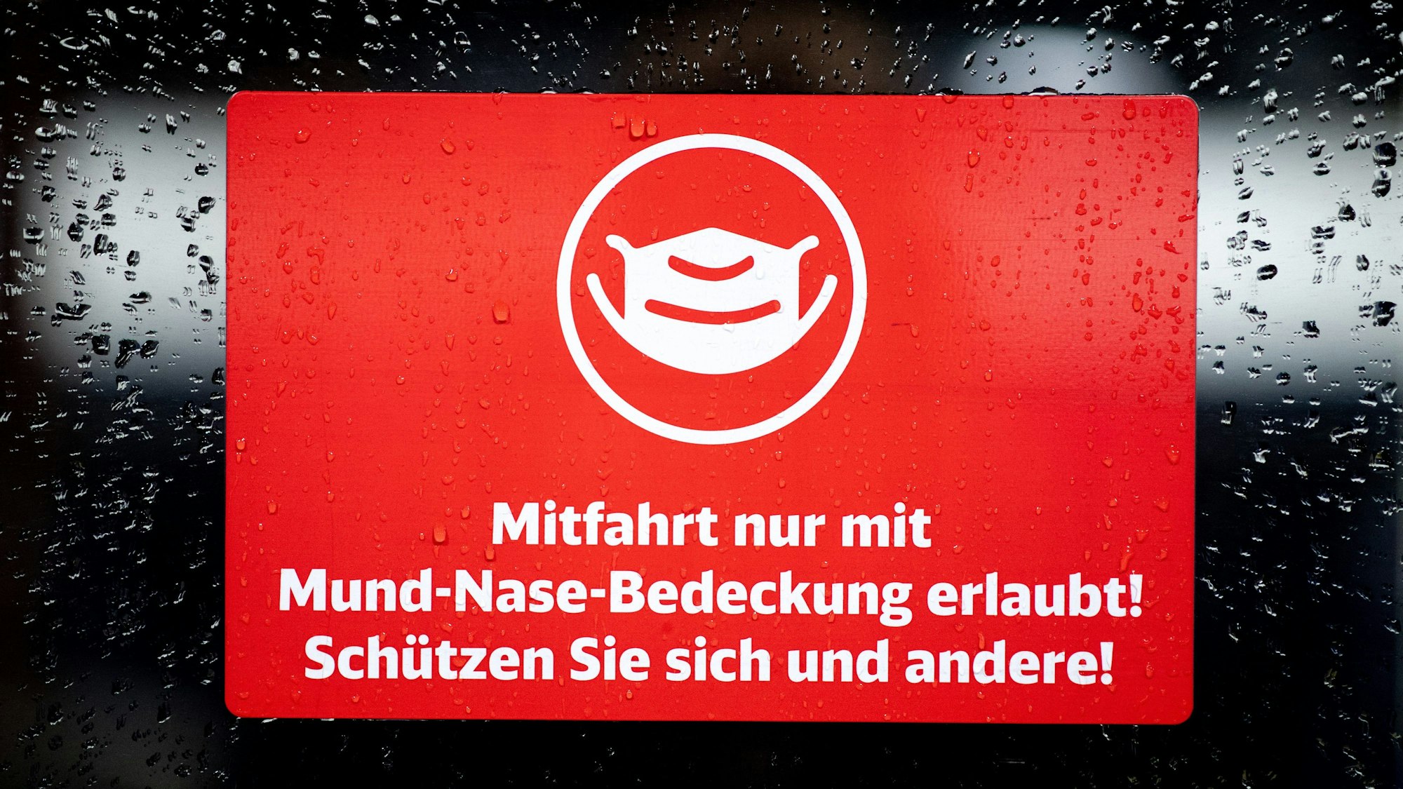 Ein Schild mit der Aufschrift „Mitfahrt nur mit Mund-Nase-Bedeckung erlaubt! Schützen Sie sich und andere!“ klebt an der Zugtür eines ICE der Deutschen Bahn
