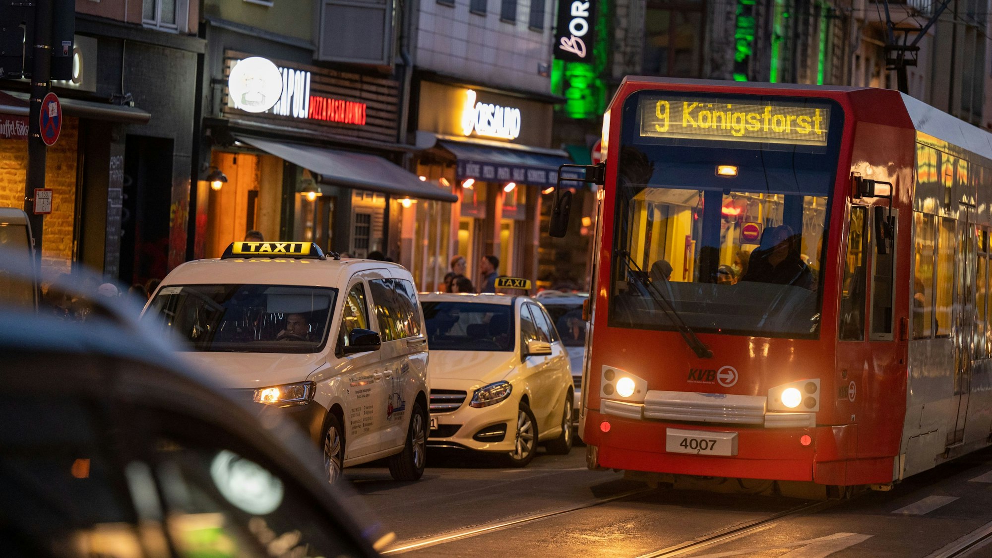 Eine Straßenbahn der Linie 9 fährt in der Dämmerung über die Zülpicher Straße.