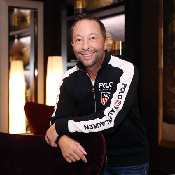 DJ Bobo in einer Sweatjacke lehnt an einem roten Sessel.