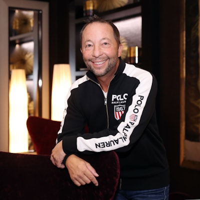 DJ Bobo in einer Sweatjacke lehnt an einem roten Sessel.