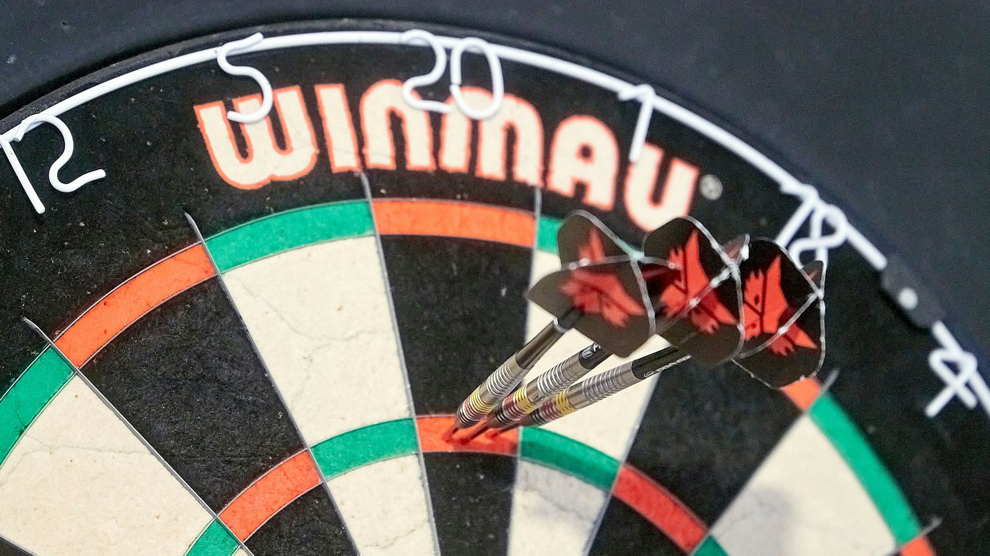 Drei Dartspfeile stecken im Feld der Triple 20.