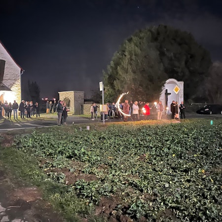 Menschenansammlung bei der Kapelle am Feld. Vereinzeltes Feuerwerk ist zu sehen.