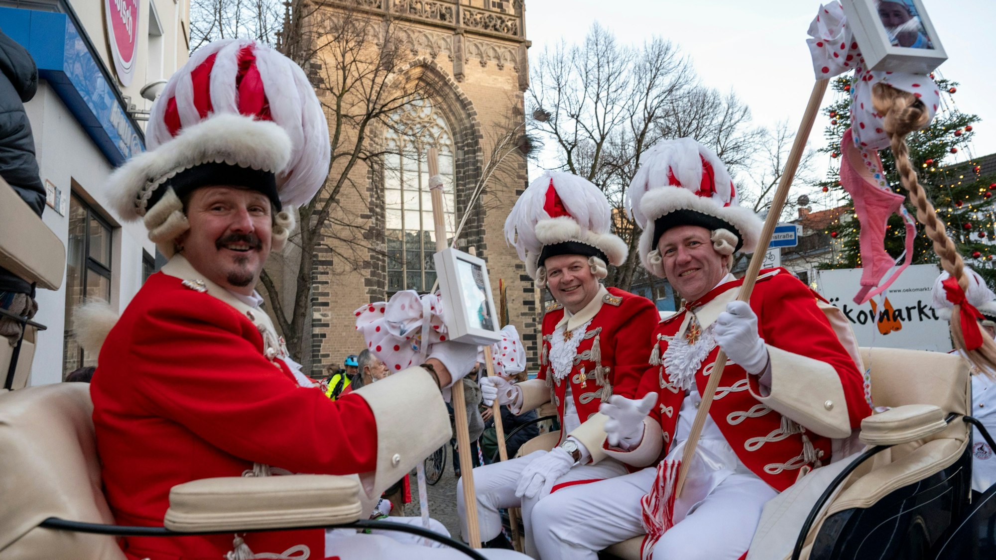 Das Dreigestirn sitzt in einer Kutsche und lächelt in die Kamera.