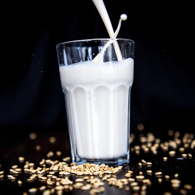 Siegeszug der Hafermilch: Ein Glas mit weißer Flüssigkeit, außen herum roher Hafer.