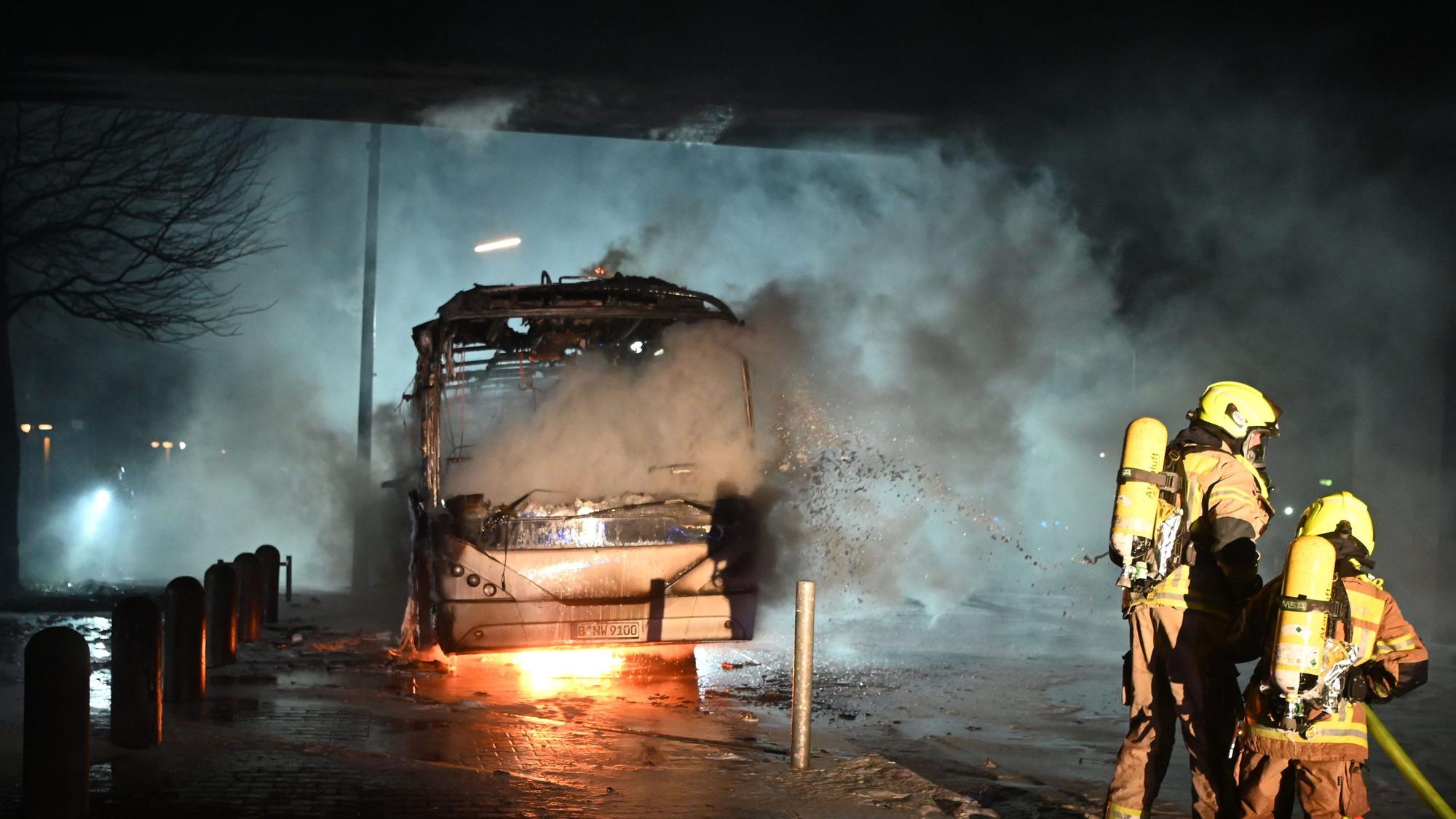 Feuerwehrmänner löschen an der Sonnenallee einen Reisebus, der von Unbekannten angezündet worden war.dpa