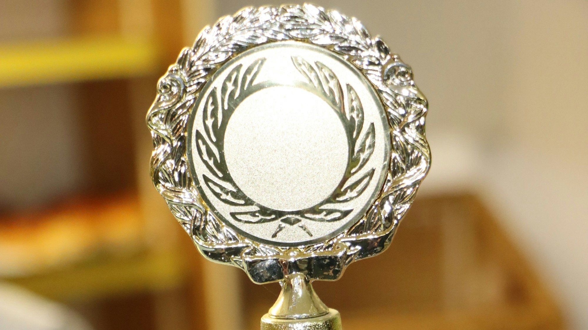 Die goldene Plakette eines Pokals. Sie zeigt einen Lorbeer-Strauch.