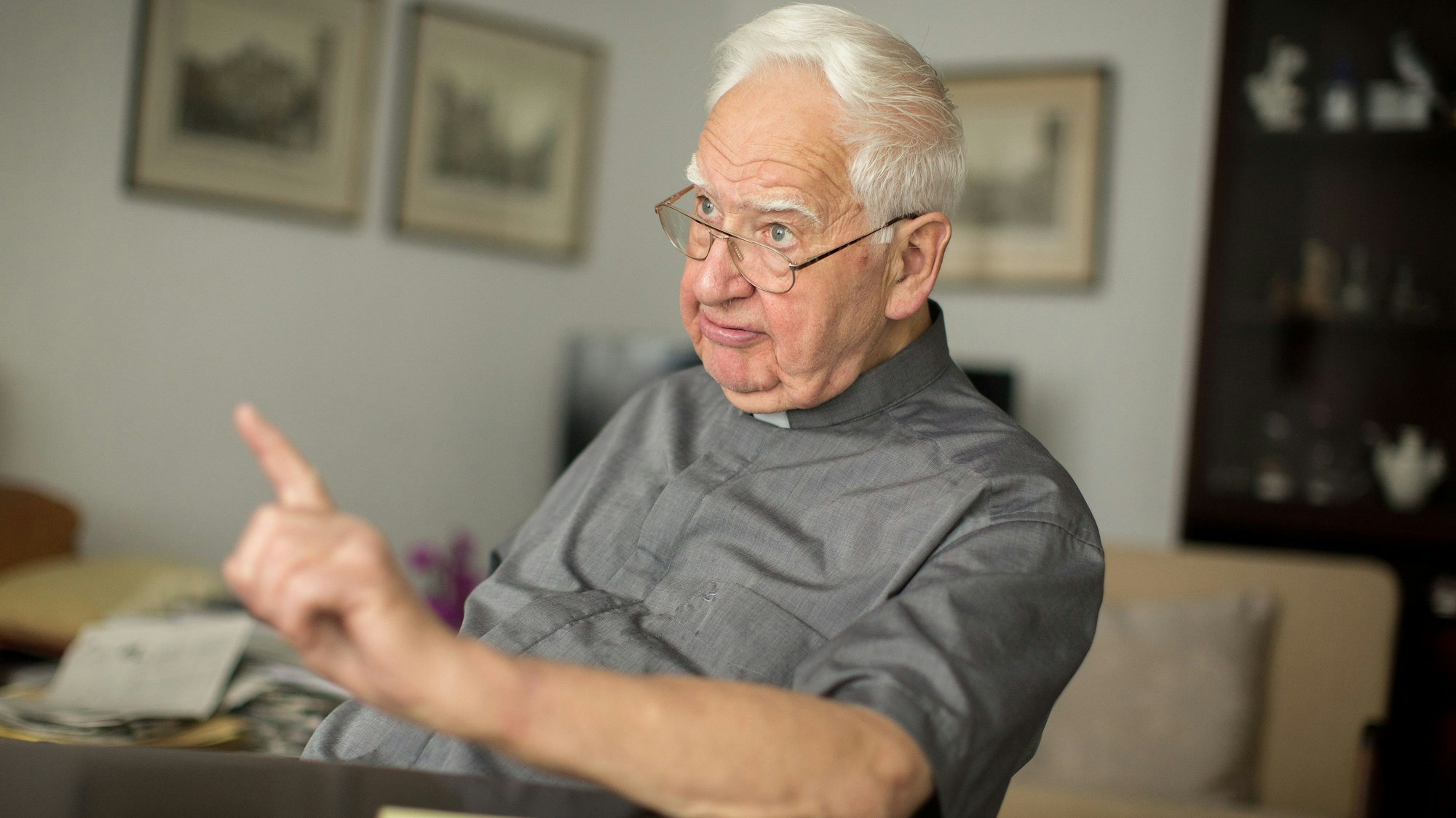 Monsignore Rolf Buschhausen sitzt an einem Tisch und hält einen Finger in die Luft.
