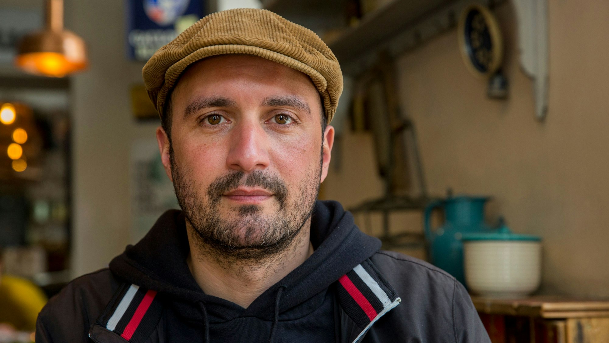 Rabe in einer seiner Gaststätten mit Schiebermütze und Trainingsjacke.