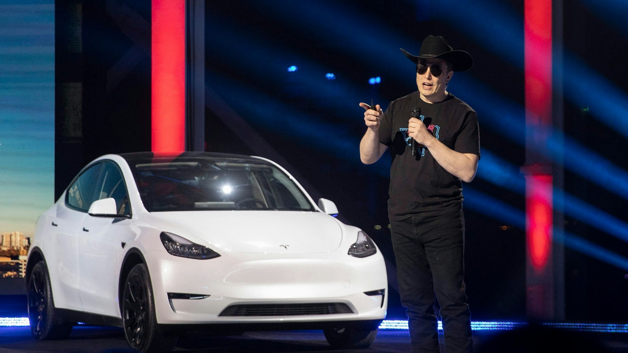 Tesla-CEO Elon Musk spricht beim „Cyber Rodeo“ im April 2022 in Texas. Hinter ihm steht ein weißer Tesla.
